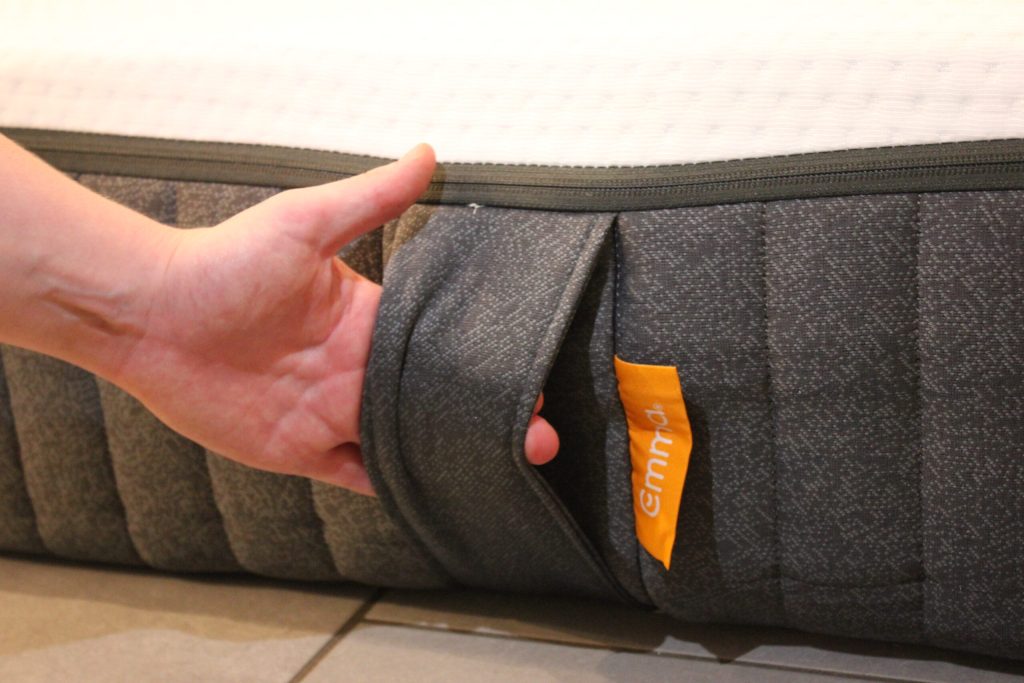 Hand pakt de handgreep aan de zijkant van de Emma Original matras