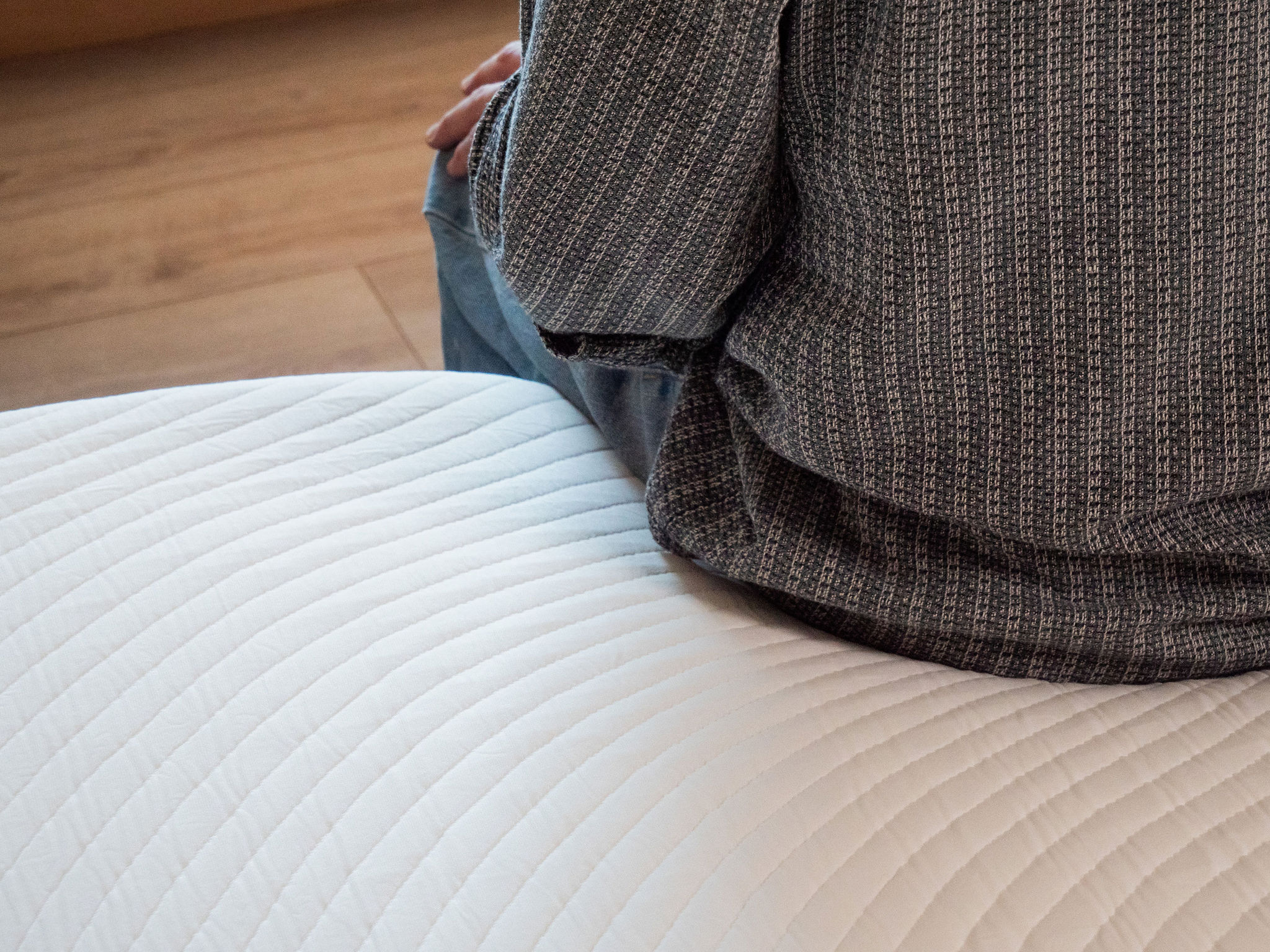 Tester zit op de Slome Originele Hybride matras met het golvende stiksel