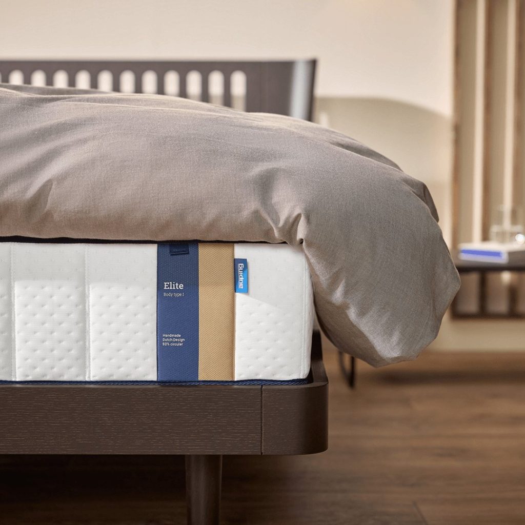 Auping Elite op een houten bed met grijs dekbed