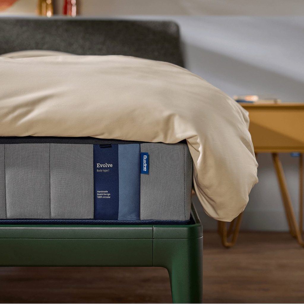 Auping Evolve op een groen gestoffeerd bed