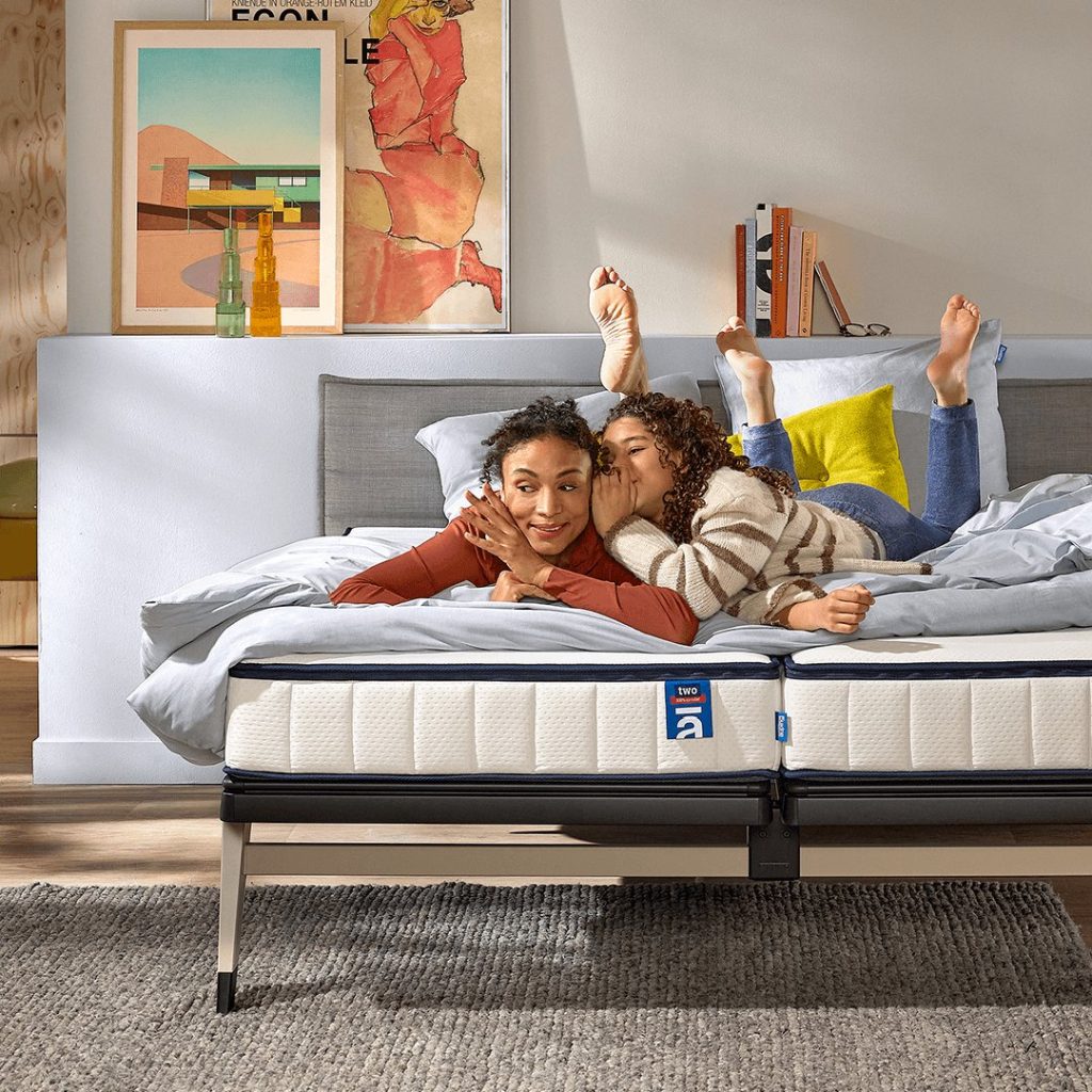 Gezin ligt lachend op een bed met de Auping Two