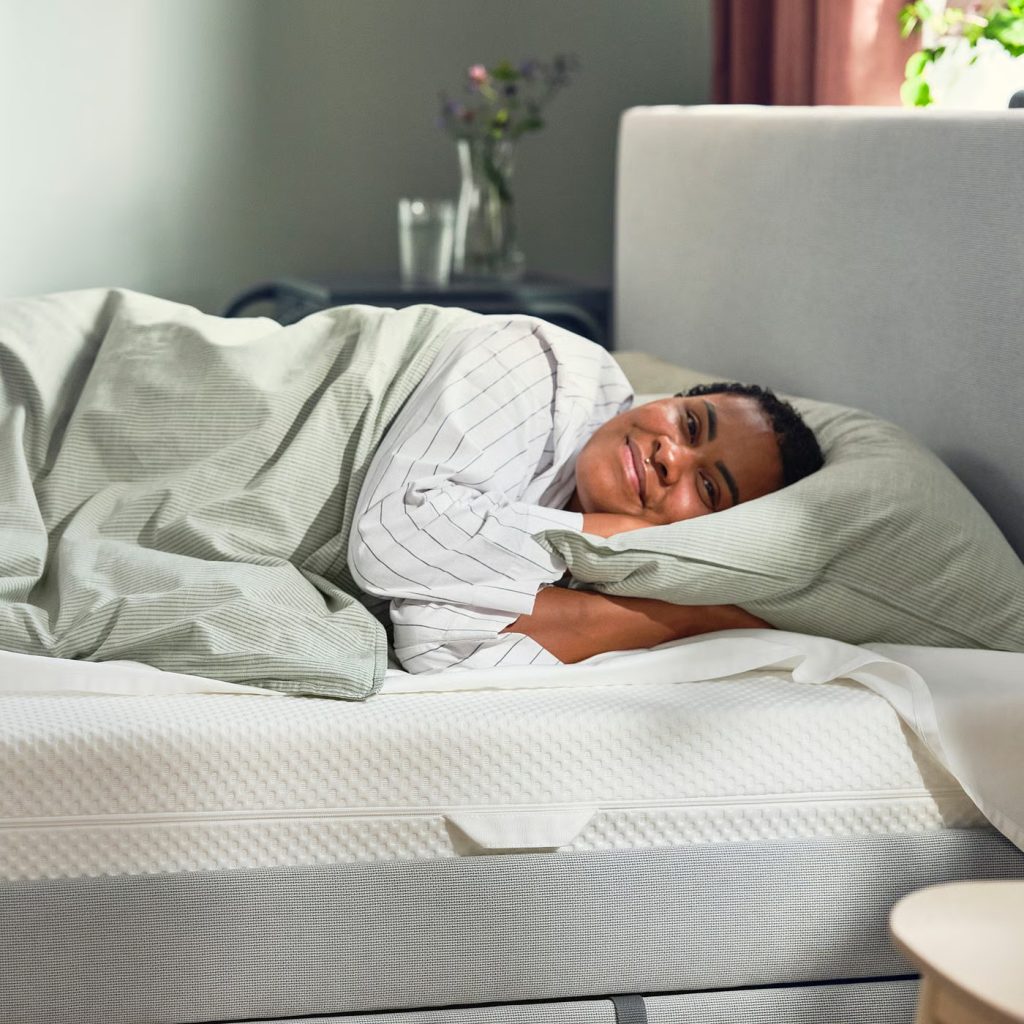 Vrouw ligt glimlachend op de IKEA Åbygda in een bedbank