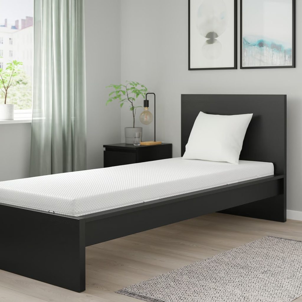 IKEA Åbygda op een smal zwart bed in een slaapkamer