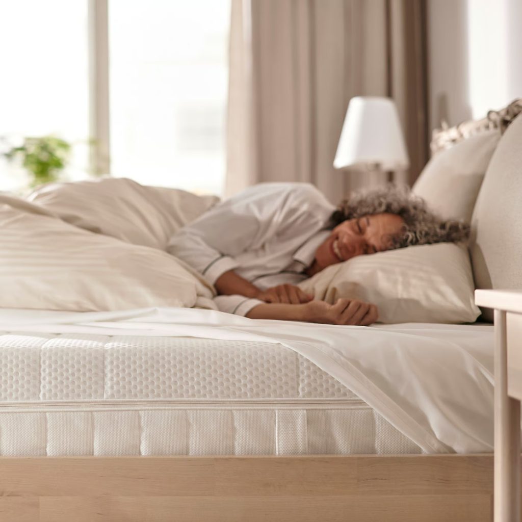 Vrouw slaapt op de IKEA Åkrehamn in een lichte slaapkamer