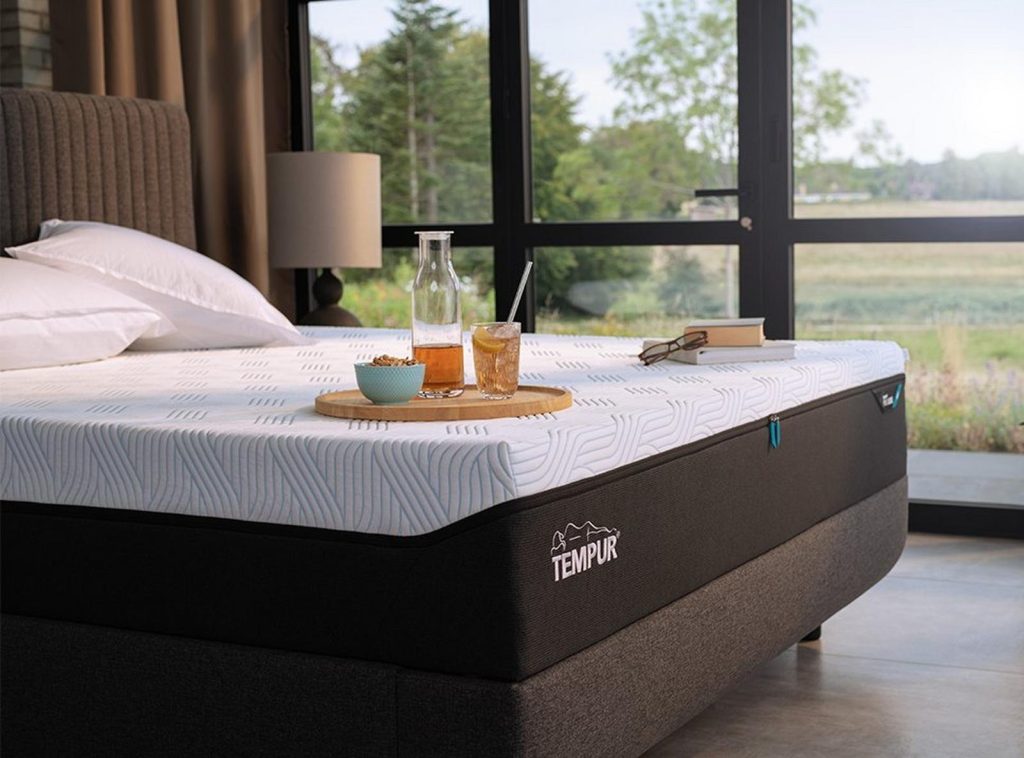 TEMPUR PRO op een bed in een kamer met groot raam