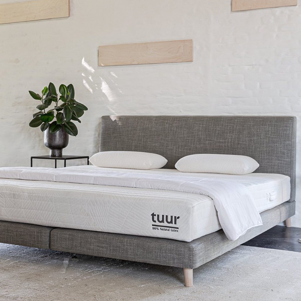 Tuur Spring op een grijze boxspring in een lichte slaapkamer